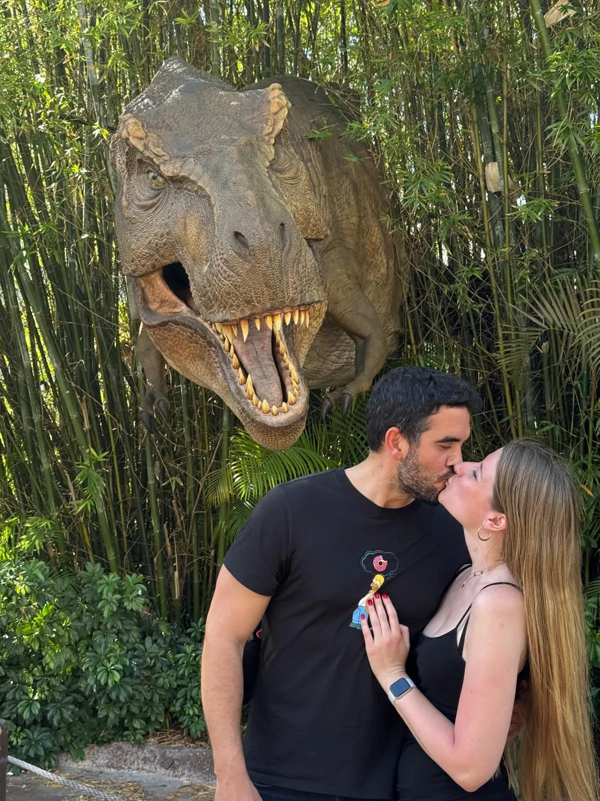 Beso delante de un dinosaurio animatrónico